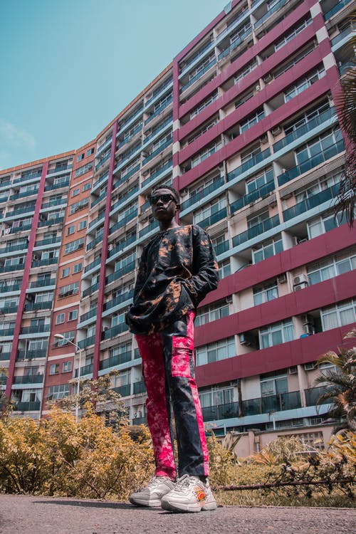 男子站在公寓楼前的低角度照片 · 免费素材图片