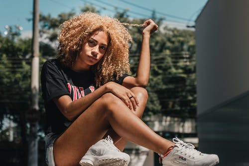 女人抱着她的头发坐在地上的照片 · 免费素材图片