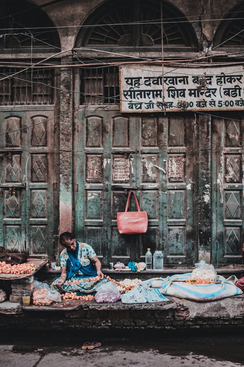 女人坐在人行道上卖水果和蔬菜 · 免费素材图片
