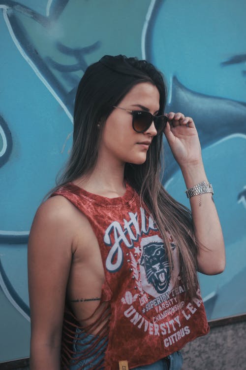 女人在红色背心和太阳镜站在涂鸦墙附近的侧视图照片 · 免费素材图片
