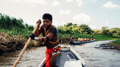 该名男子手持木桨骑在蓝船上的特写摄影 · 免费素材图片