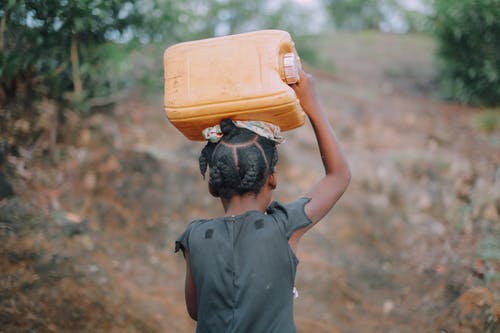 儿童背着水罐的照片 · 免费素材图片
