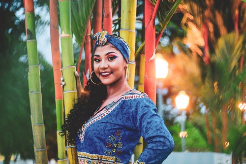 在传统的非洲服装，站在树旁的微笑妇女的选择性焦点照片 · 免费素材图片