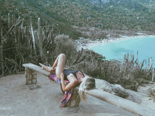 女人穿着黑色泳装，躺在长椅上 · 免费素材图片