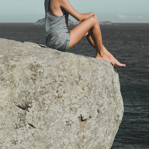 女人坐在灰色的石头上 · 免费素材图片