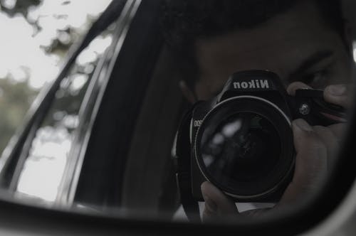 男子手持尼康相机的思考 · 免费素材图片