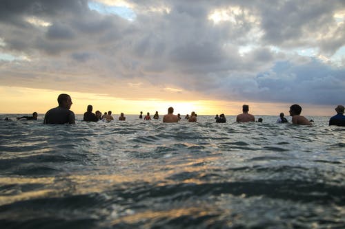 日落期间人们在海洋中的照片 · 免费素材图片