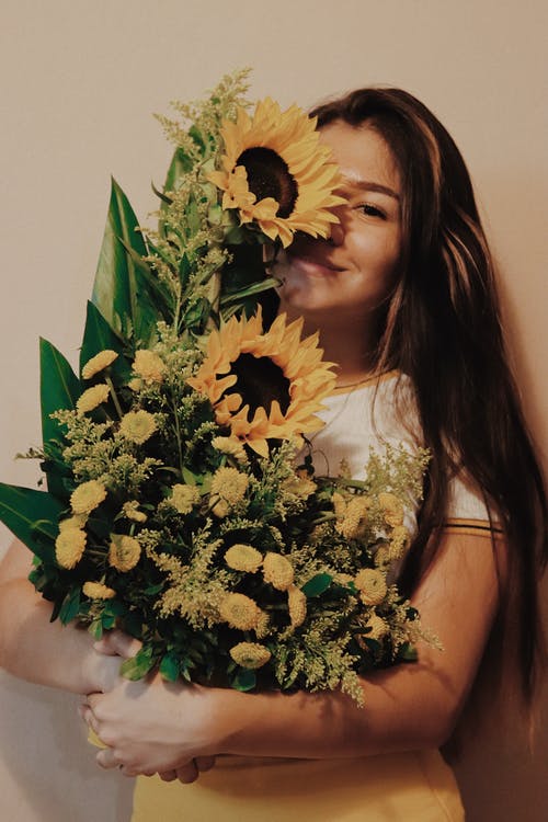 微笑的女人背着向日葵的照片 · 免费素材图片