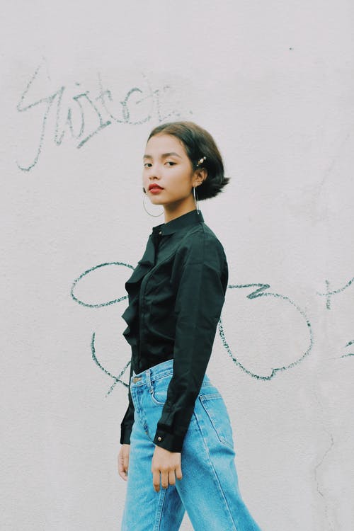 女人站在附近墙上有一些黑色文字的侧视图照片 · 免费素材图片