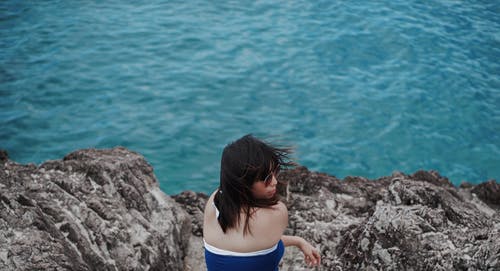 一个女人坐在岩石上的照片 · 免费素材图片