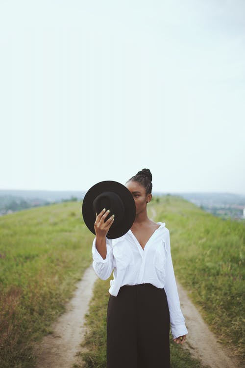 女人穿着白色上衣举行软呢帽的照片 · 免费素材图片