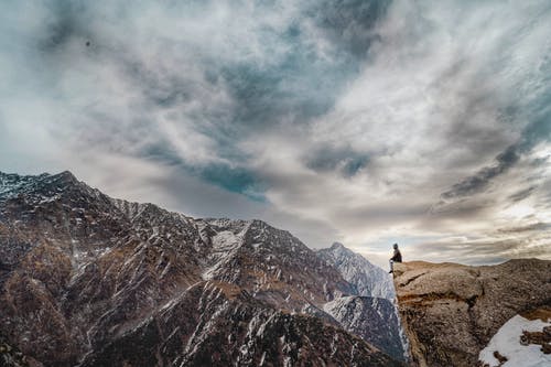 男子坐在山峰上 · 免费素材图片