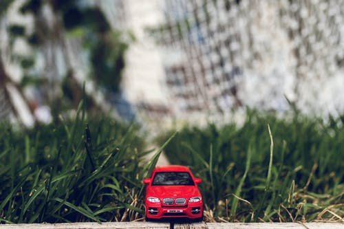 在绿色草地上的红色汽车玩具 · 免费素材图片