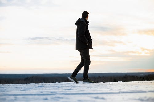 黑色连帽外套和裤子在雪地上行走的人 · 免费素材图片