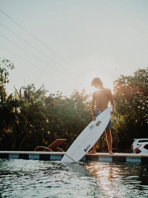 男子站在混凝土控股冲浪板 · 免费素材图片