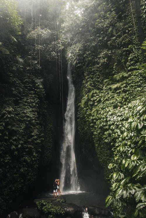 女人和男人站在瀑布下 · 免费素材图片