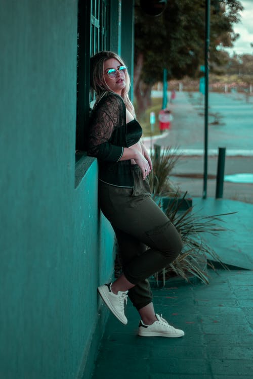 女人在靠在墙上的太阳镜的侧视图照片 · 免费素材图片