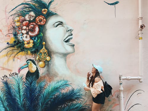 站在涂鸦墙旁边的笑女人的侧视图照片 · 免费素材图片