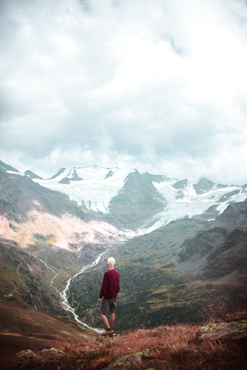 身穿红色毛衣站在山上的人 · 免费素材图片