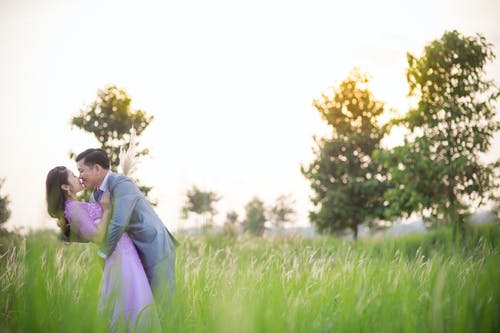 男人在草地上亲吻女人的浅焦点照片 · 免费素材图片