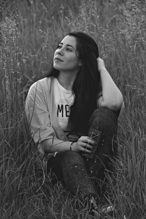 女人坐在草地上的单色照片 · 免费素材图片