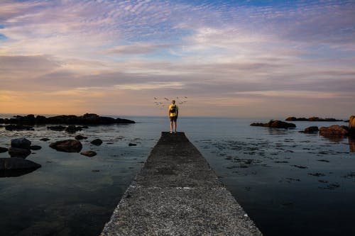 一个人站在海码头上的照片 · 免费素材图片