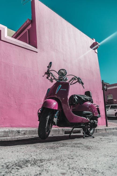 粉红色的摩托车停在粉红色的墙壁旁边的照片 · 免费素材图片