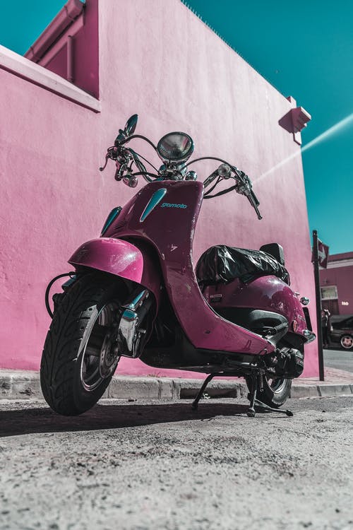 粉红色的摩托车停在粉红色的混凝土墙旁边 · 免费素材图片