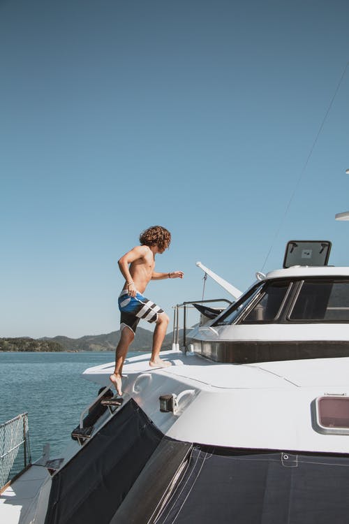 男子爬上游艇的照片 · 免费素材图片