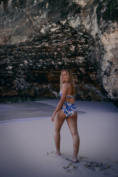 蓝白比基尼泳装的微笑女人的照片在海边漫步 · 免费素材图片