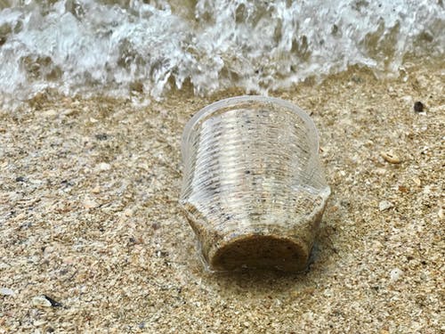 塑料杯在沙滩上的特写照片 · 免费素材图片