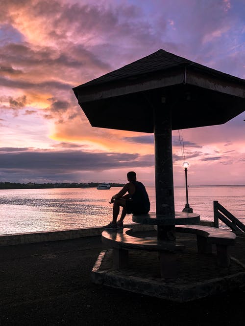 男子坐在桌子上看日落美景 · 免费素材图片