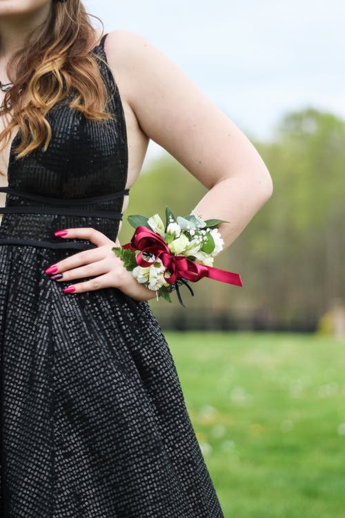 女人穿着黑色的连衣裙和花手链 · 免费素材图片