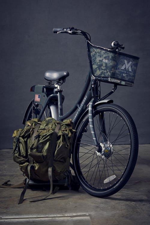 绿色背包旁的黑色通勤自行车 · 免费素材图片