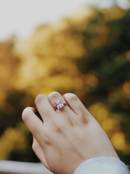 戴银戒指配粉红色宝石的人 · 免费素材图片