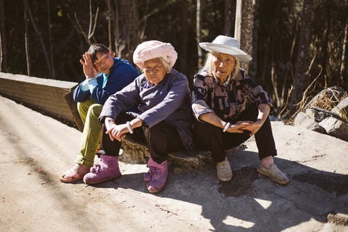 三人坐在人行道旁 · 免费素材图片