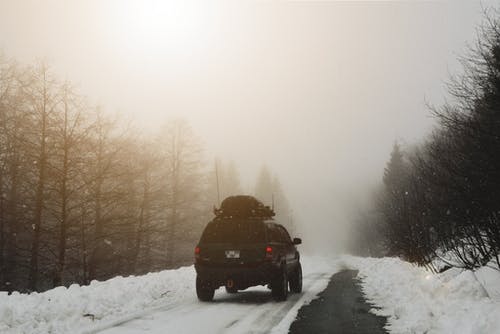 黑色车辆在积雪覆盖的路上行驶 · 免费素材图片