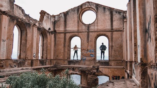男人和女人站在棕色的混凝土建筑 · 免费素材图片