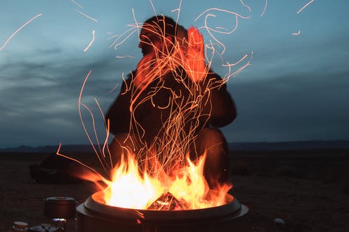 夜间坐在锅中面对火的人 · 免费素材图片