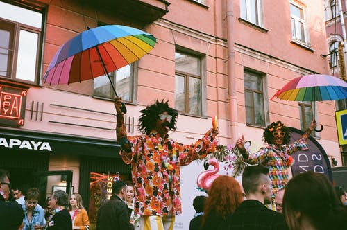 两个男人拿着彩虹色的雨伞在舞台上表演 · 免费素材图片
