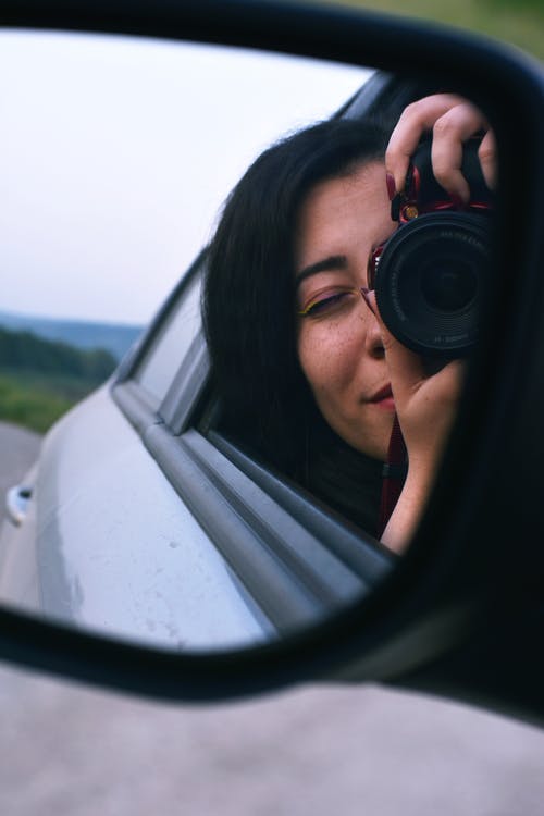 女人在车镜上拍照 · 免费素材图片