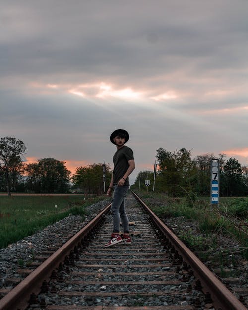 站在火车轨道构成中间的人的侧视图照片 · 免费素材图片
