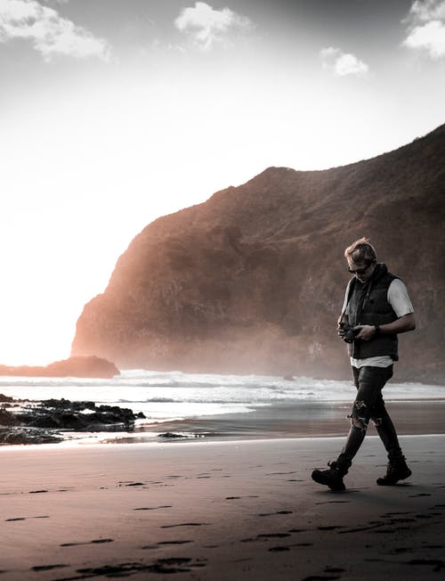 男子走在海滩线附近 · 免费素材图片