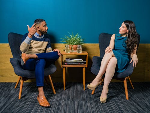 女人穿着蓝绿色的裙子，坐在椅子上与男人交谈 · 免费素材图片