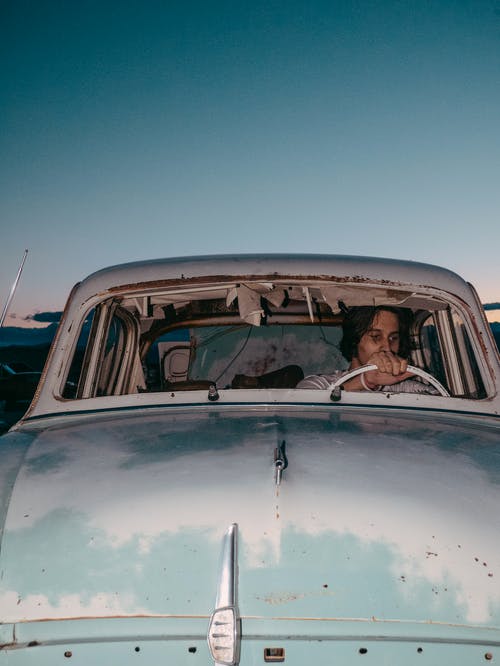 坐在旧的废弃老爷车内的人的照片 · 免费素材图片