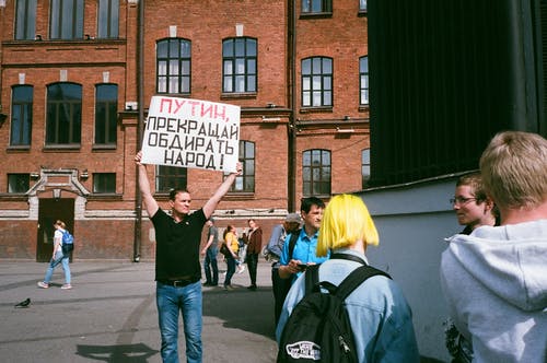 男子手持标志站立在室外 · 免费素材图片