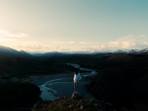 男子站在悬崖边缘附近的岩石上的照片 · 免费素材图片