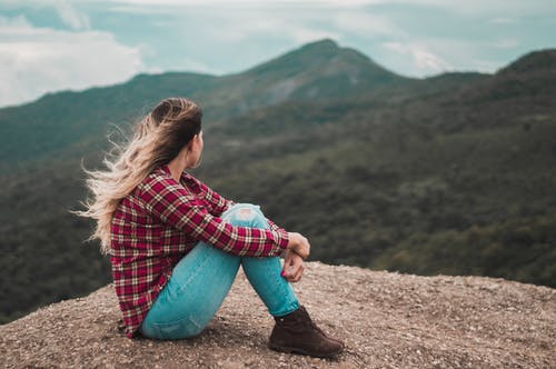 女人坐在俯瞰山的地面上的侧视图照片 · 免费素材图片