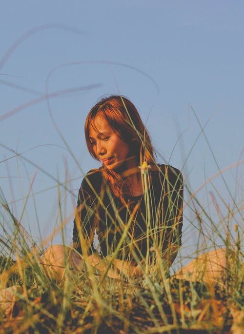 坐在草地附近的女人的照片 · 免费素材图片