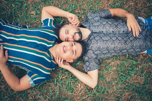 两名男子躺在绿色的草地上 · 免费素材图片